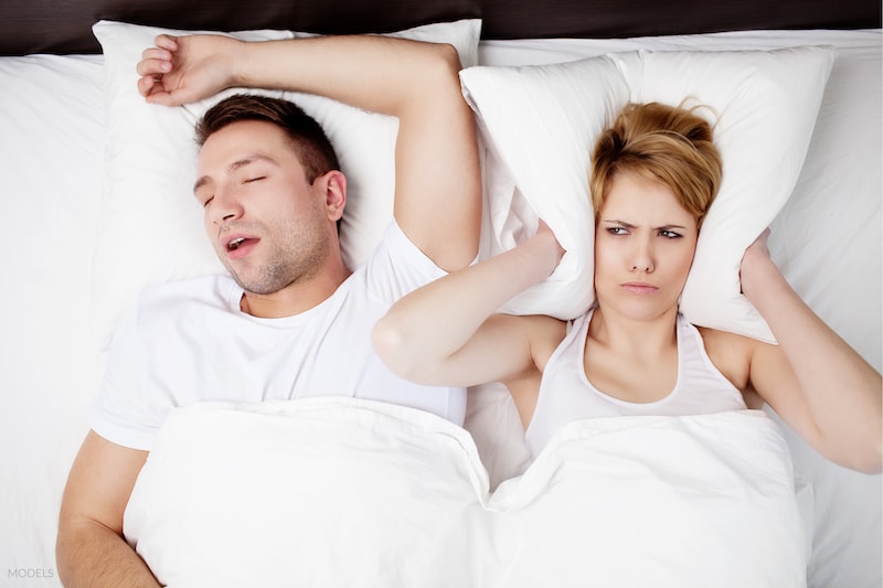 Snoring man annoying young woman in bed.