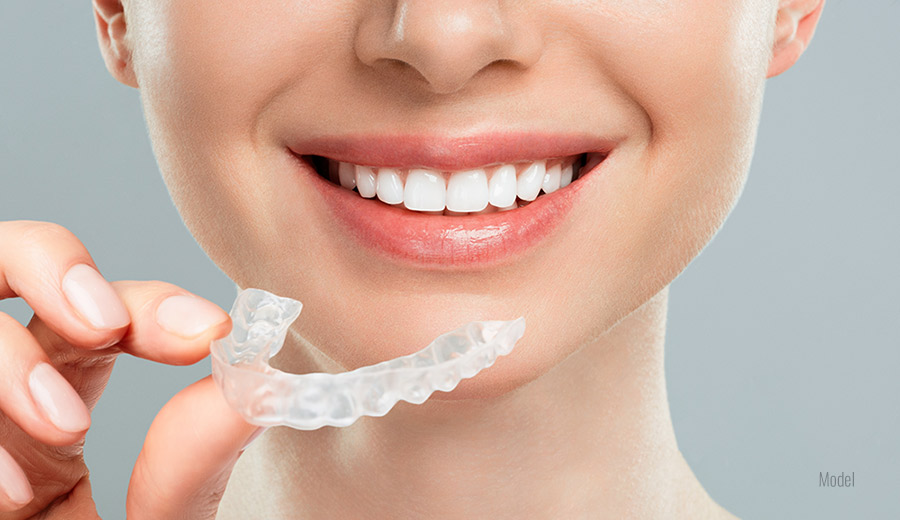 A close-up of a woman holding her clear dental aligners.