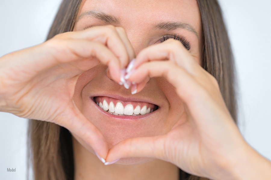 women with healthy smile and heart shape with her hands